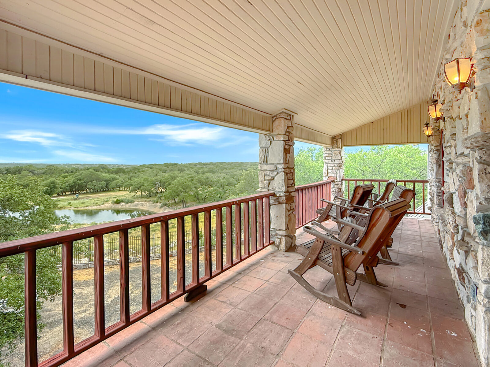 Covered rocking-chair porch on the lodge looking out over the oaks and the pond