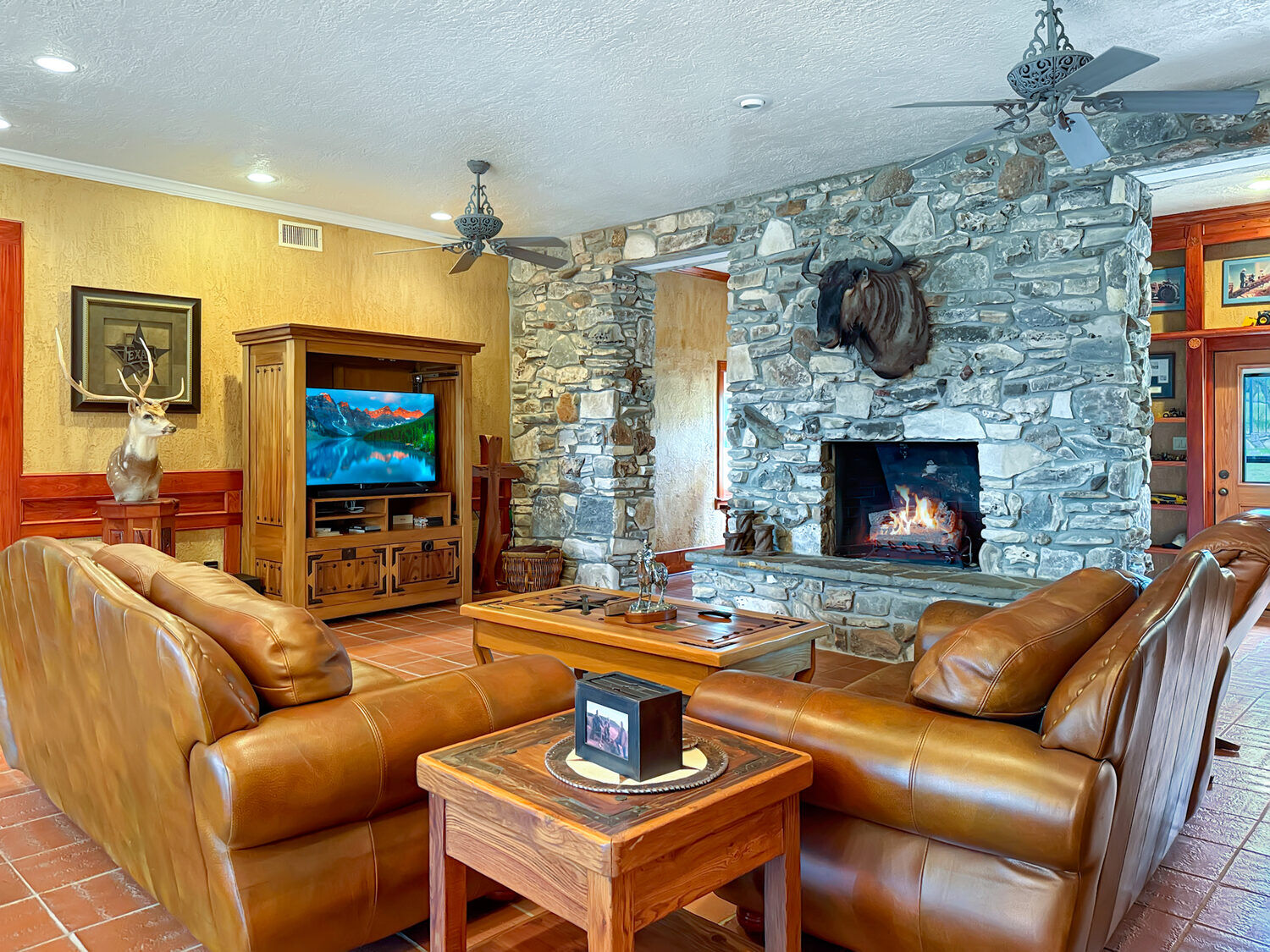 Great room with a floor-to-ceiling stone fireplace, leather seating and saltillo tile