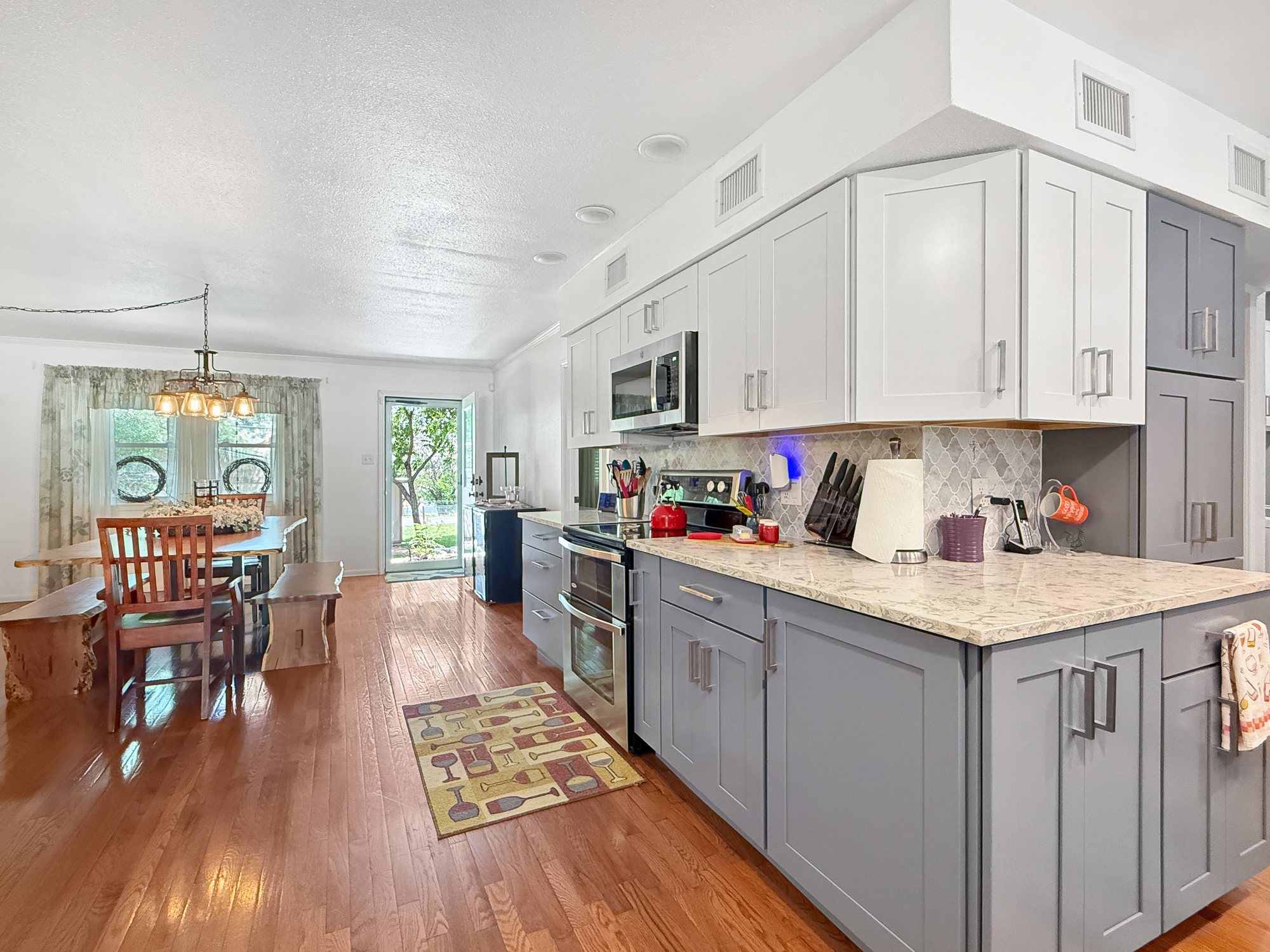 The remodeled kitchen at 1406 N Harper Rd looking through to the dining area, with two-tone cabinetry, stone counters and wood floors