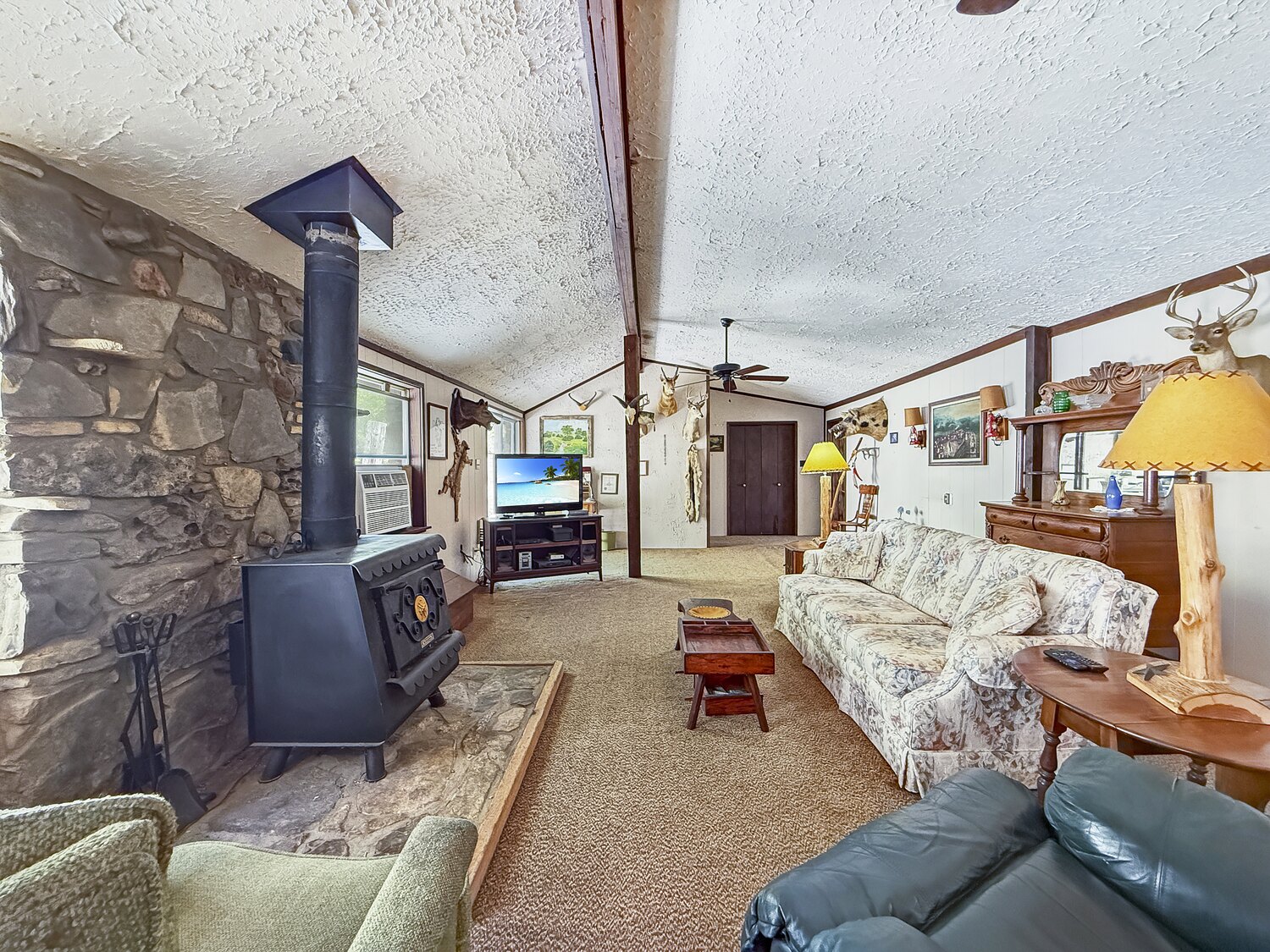The living room at 150 Coker Hollow with a wood-burning stove on a stone hearth against a stone wall