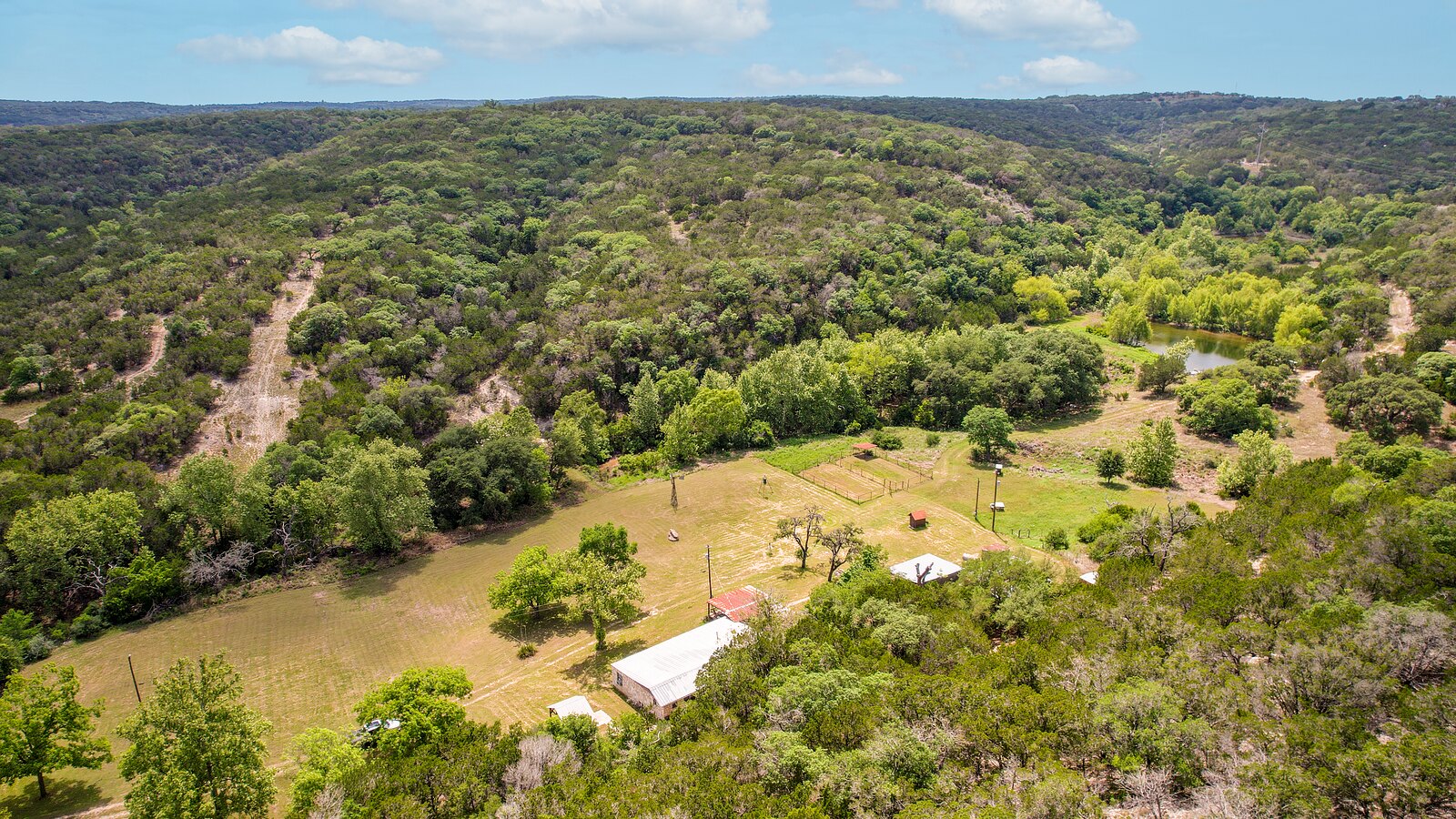 Aerial of the whole box canyon at 150 Coker Hollow showing the meadow, the buildings, the pond and the wooded ridges around them