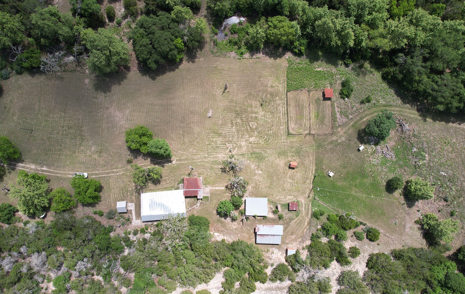 Overhead aerial directly above the homestead at 150 Coker Hollow showing the house, sheds, corrals and the mowed meadow