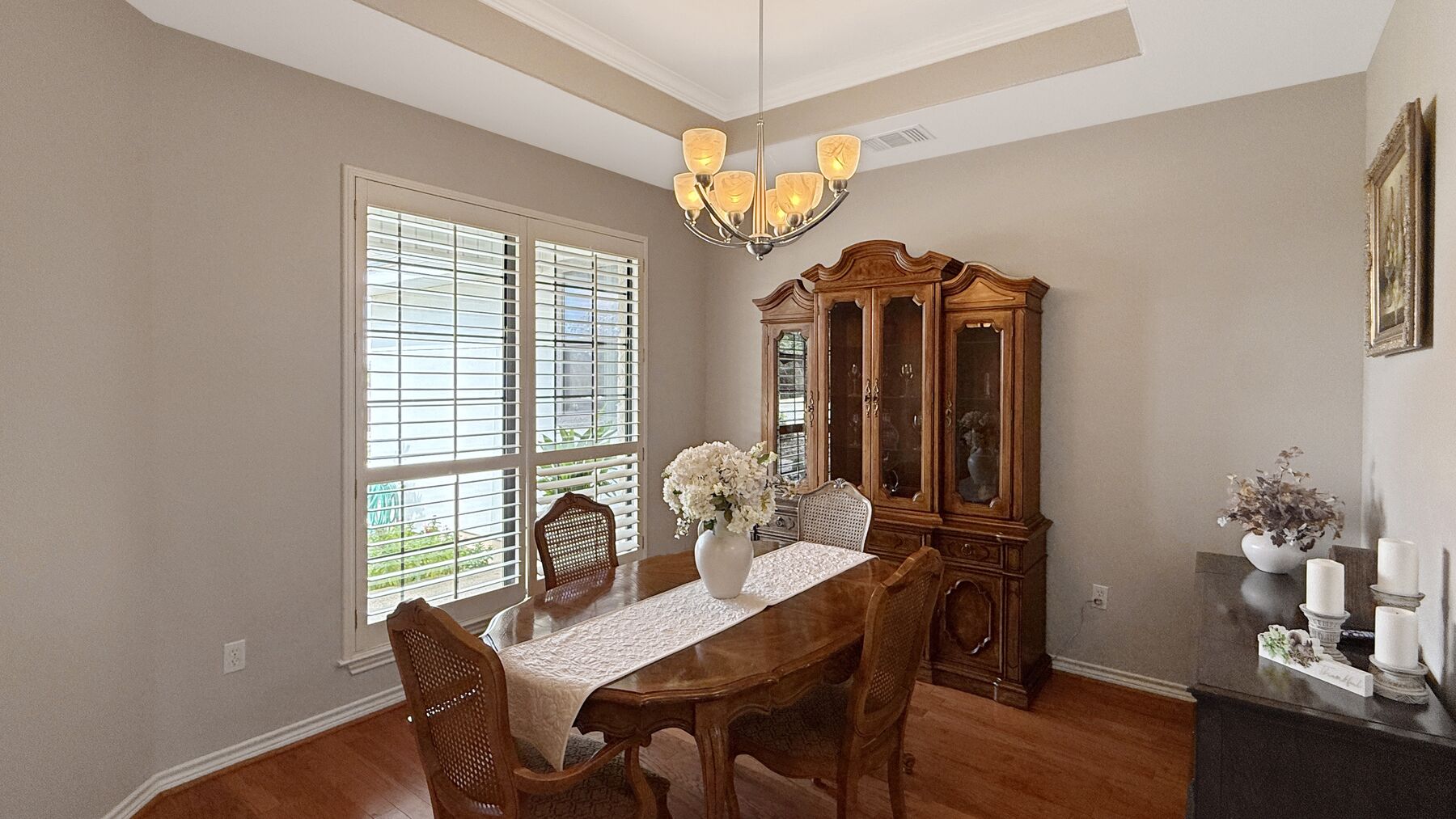 The dining room at 2004 Athens Ave — wood floors under a tray ceiling with a chandelier, and a window to the front of the house