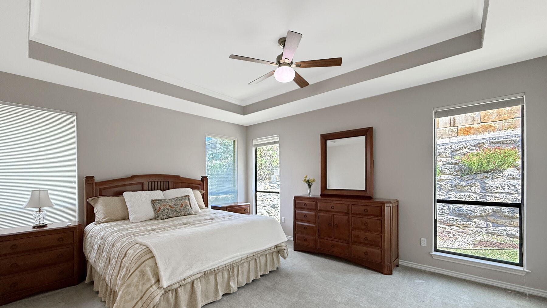 The primary bedroom at 2004 Athens Ave under a tray ceiling with a ceiling fan, windows on two walls and carpet underfoot