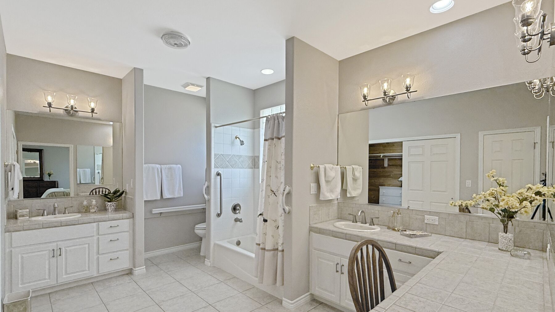 The primary bathroom at 2004 Athens Ave — tile counters and twin vanities either side of a tub-and-shower alcove, with a seated station at the right-hand counter
