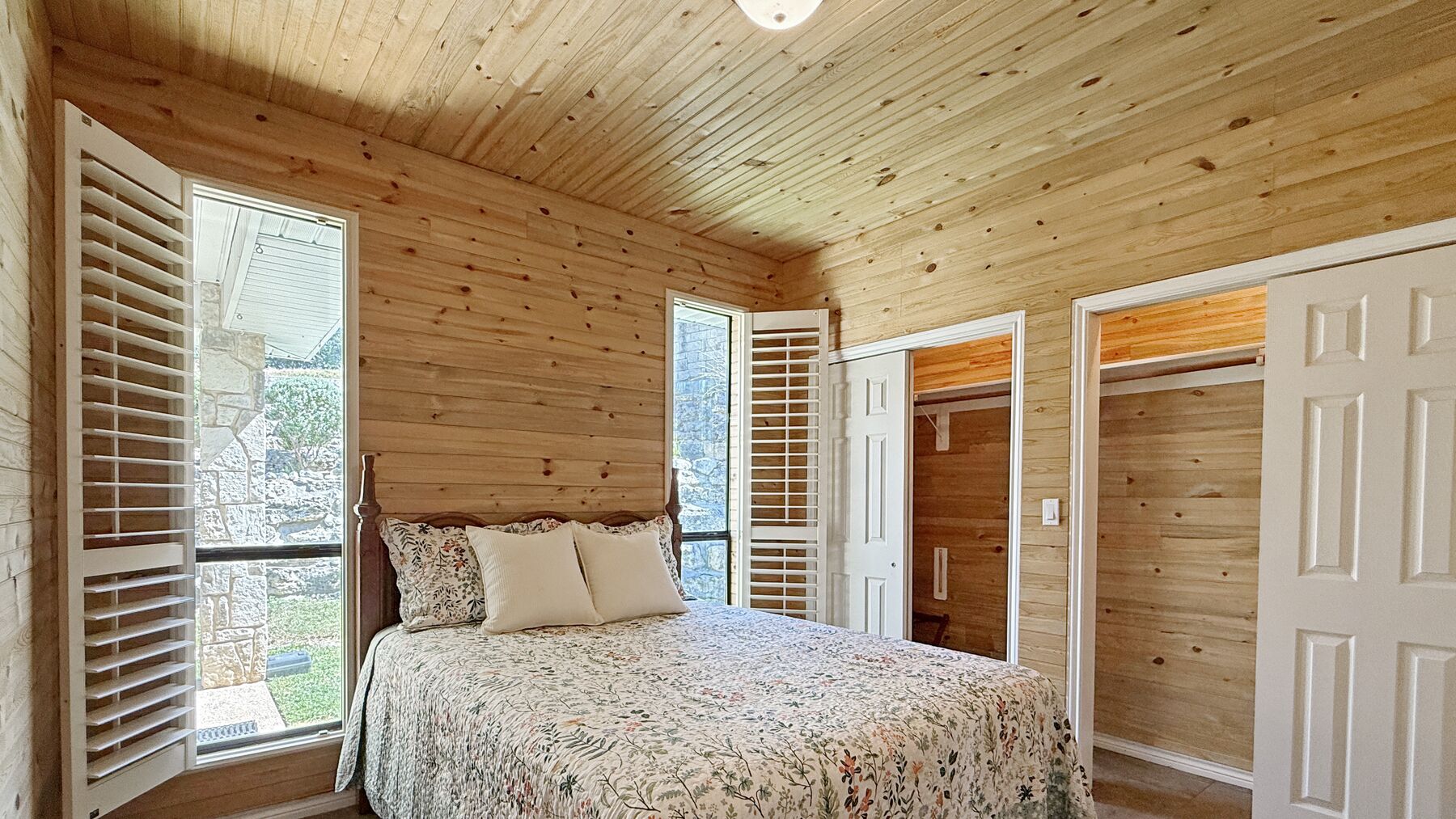 A second bedroom at 2004 Athens Ave with cedar plank walls and ceiling, plantation shutters and a tile floor