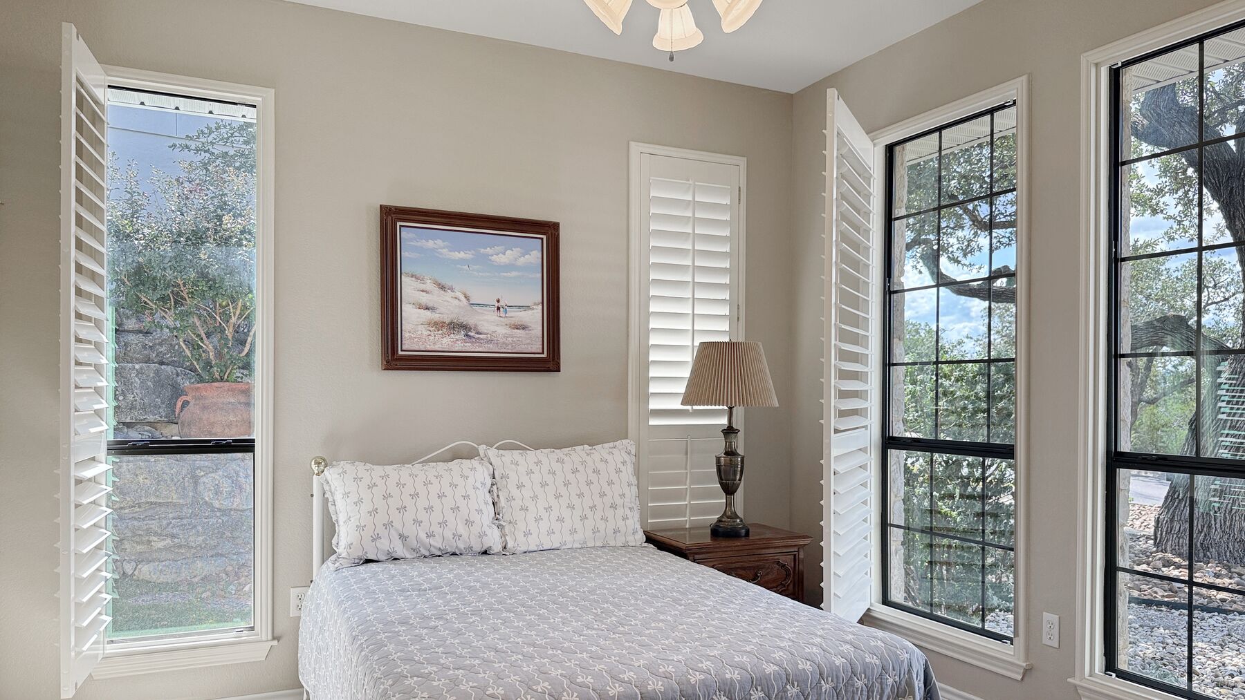 The third bedroom at 2004 Athens Ave with tall black-framed windows, plantation shutters and a view into the oaks