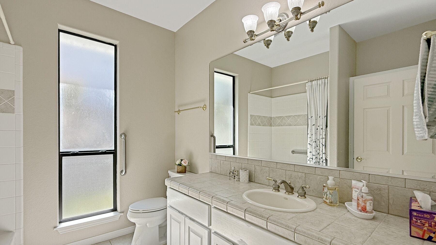 The second full bathroom at 2004 Athens Ave — tile counters, a shower and an obscure-glass window