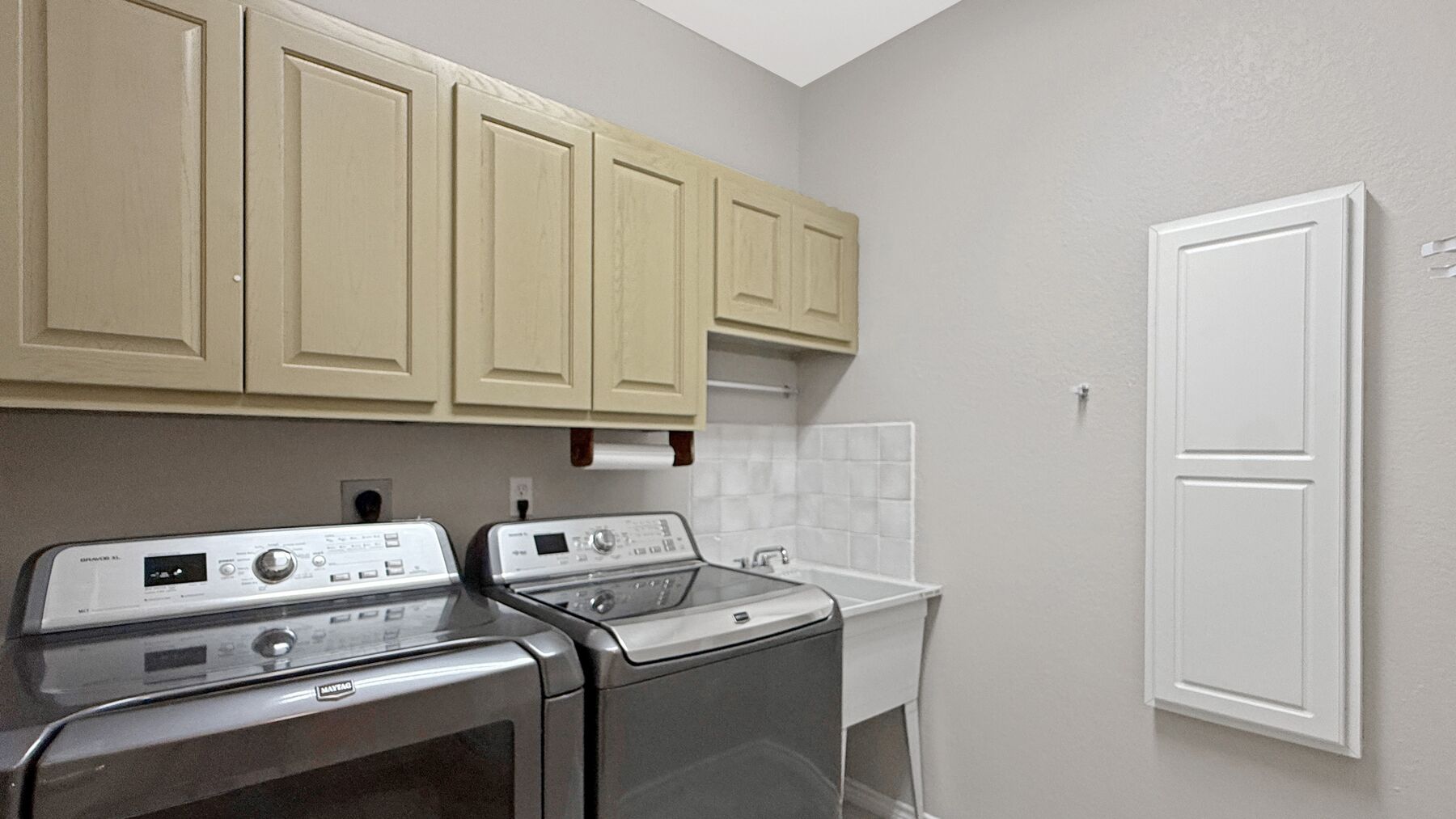 The utility room at 2004 Athens Ave — a washer and dryer under wall cabinets, with a folding counter beside them