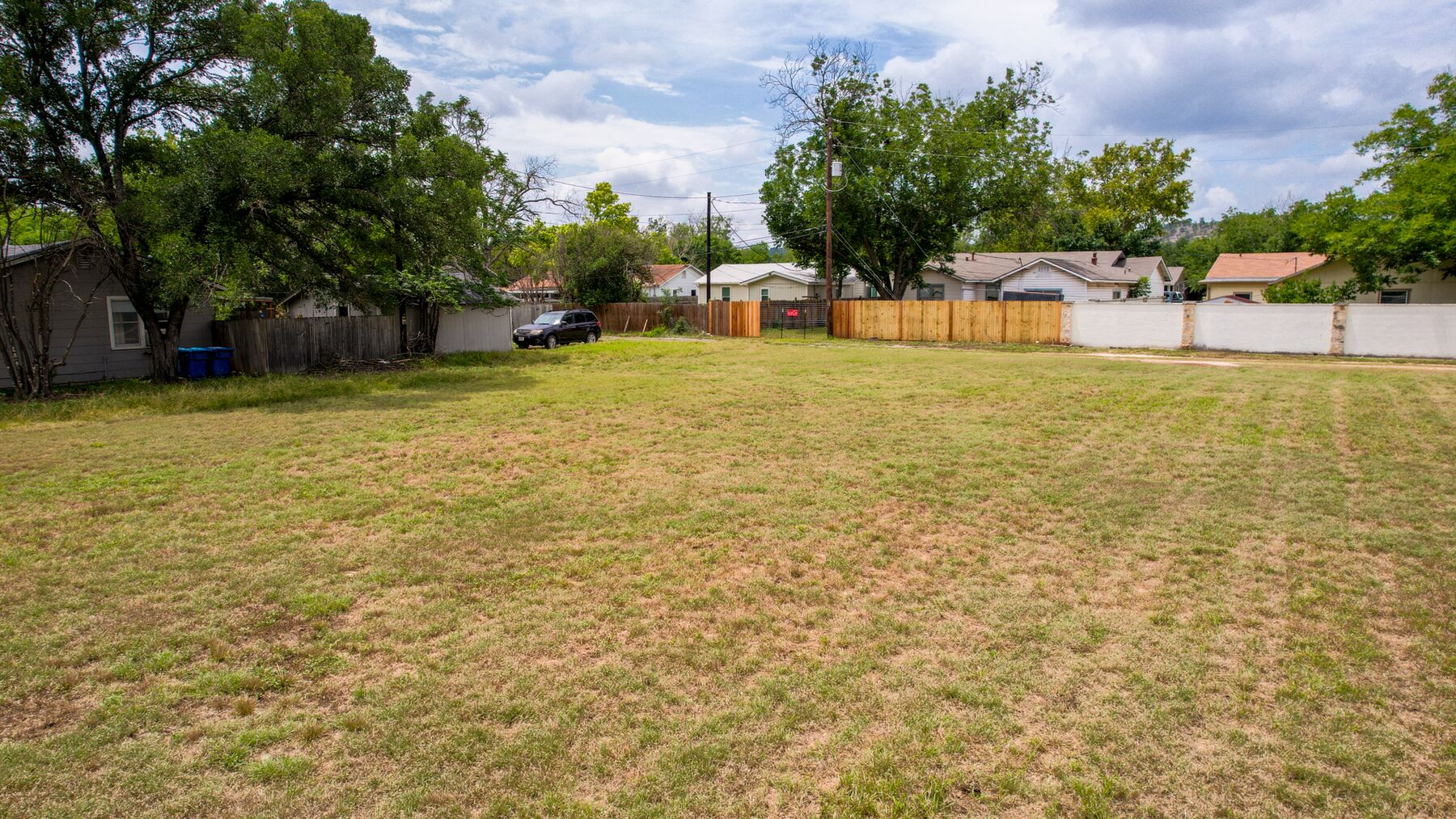 The rear portion of the property, looking toward the wood fences of the adjoining back yards. A vehicle parked on the day of the photography appears at the left; it is not part of the property.